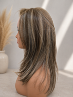 A shoulder-length layered wig with ash brown and blonde highlights, displayed on a mannequin head in profile against a neutral background.