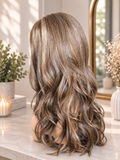 Long wavy wig with highlighted brown and blonde tones, shown from the back on a mannequin head in a softly lit indoor setting.